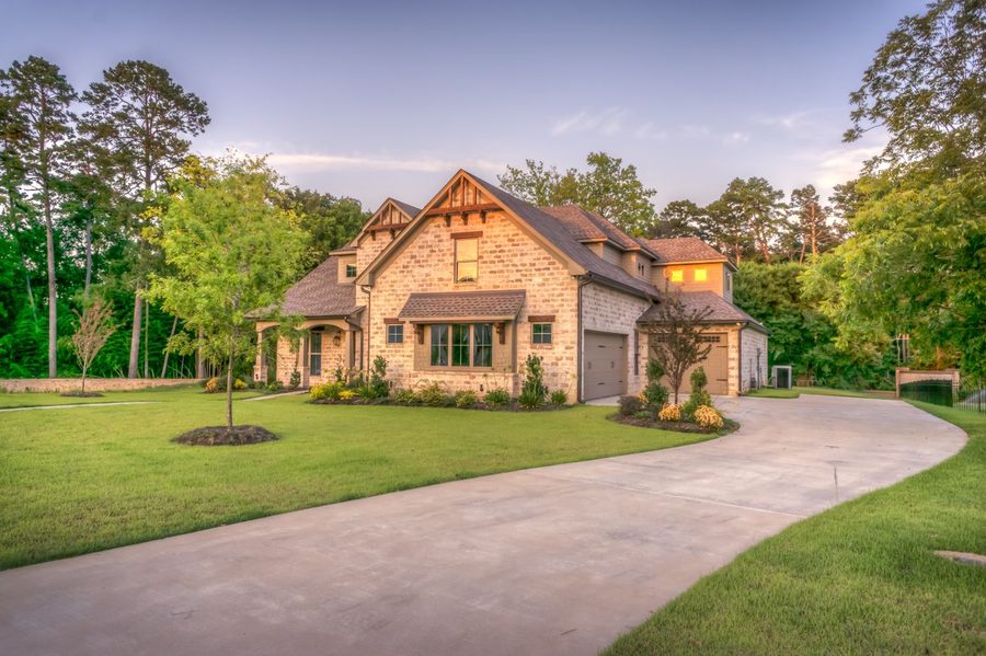Luxury stone-clad estate home with landscaped grounds at dusk